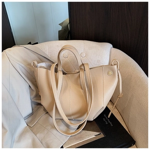 Detailansicht der hochwertigen Lychee-Textur und Mehrschichtnähte an der beigen Handtasche
