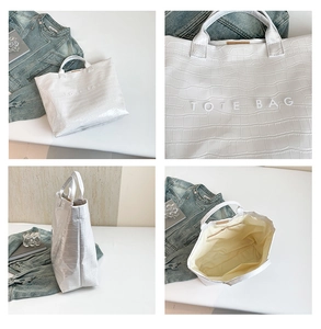 Detail view of large white tote bag with crocodile texture and interior zipper pockets