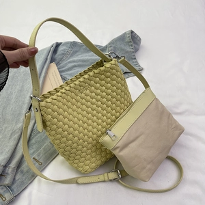 Green leather woven bucket bag with beige canvas inner pouch and adjustable strap