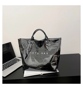 Detail of glossy black crocodile embossed tote bag with white TOTE BAG lettering text