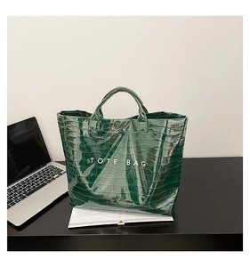 Detail of dark green crocodile pattern tote bag with TOTE BAG print on office desk