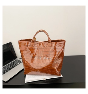 Close-up of brown crocodile pattern tote bag with TOTE BAG print on office desk