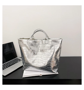 Detail of silver metallic tote bag with stone pattern texture and embossed lettering