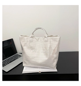 Close-up of white crocodile pattern tote bag with TOTE BAG embossed text details