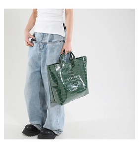 Deep green crocodile embossed tote bag with white text print shown on a model