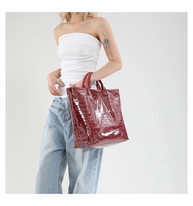 Close-up of red crocodile pattern tote bag with TOTE BAG text print and shiny finish