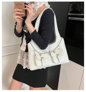 Close-up of white faux leather tote with heart charms and silver buckle pockets
