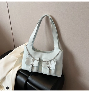 Close-up of light blue leather shoulder bag with silver chains and heart charms