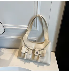 Detail of cream PU leather tote bag featuring double pockets and silver metal chain charms