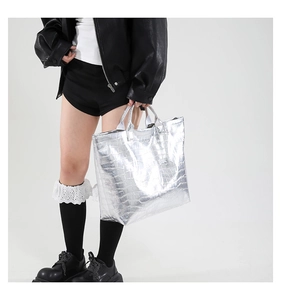 Close-up of silver tote bag featuring crocodile embossed texture and metallic finish