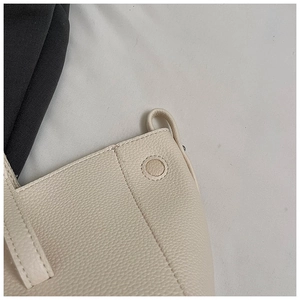 Detail der beigen Handtasche aus Narbenleder mit feiner Naht und rundem Leder-Verschluss