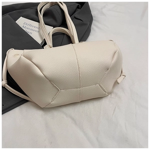 Detailansicht der cremeweißen Handtasche mit Litschistruktur und modernen Geometrie-Nähten