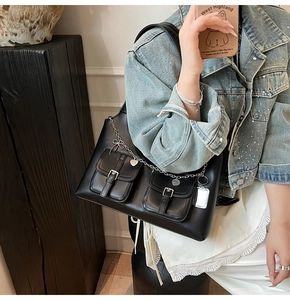 Detail of black leather tote bag with silver butterfly chains and moto punk buckle pockets