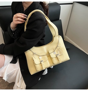 Detail of pale yellow leather shoulder bag with silver chains and heart charms