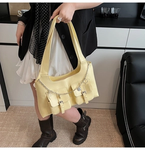 Detail of yellow leather tote with utility pockets and silver chain ornament
