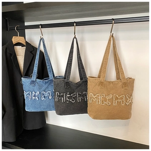 Hanging denim tote bags in blue, grey, and yellow with frayed letter patch details