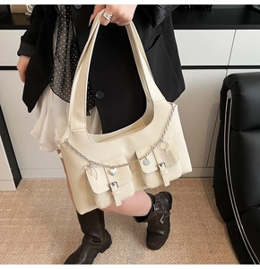Detail of off-white shoulder bag with metallic buckle pockets and silver heart chain