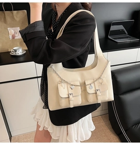 Detail view of cream PU leather tote bag with silver chains and decorative mini pockets