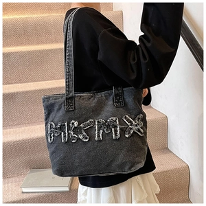 Detail of gray washed denim tote bag with MIKMAX applique embroidery and vintage texture