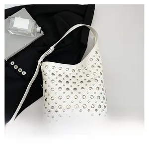 Gros plan d'un sac seau blanc avec des rivets argentés et une finition en cuir mat