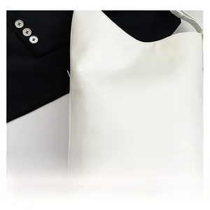 Détail d'un sac cabas en cuir blanc avec ouverture en V posé sur un vêtement noir