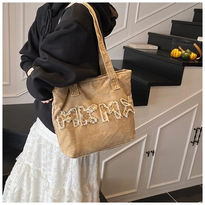 Close-up of vintage washed canvas tote bag with MKMA frayed letter applique detail