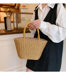 Detail of handmade woven straw tote with metallic gold base and natural fiber handles