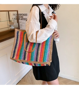 Detail of colorful striped woven tote bag featuring durable brown leather shoulder straps