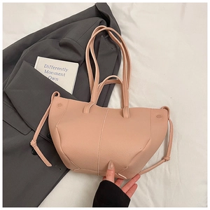 Detailansicht der hellrosa Schultertasche mit Lederstruktur auf einem grauen Anzug liegend
