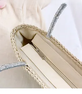 Detail view of the secure silver zipper closure and lining on the straw woven tote bag
