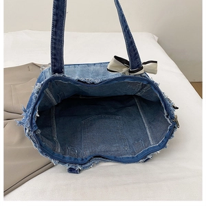 Detail of denim tote bag with internal pocket, zipper, and decorative bow knot