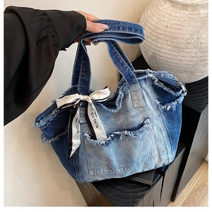 Detail of frayed edge denim tote bag with ribbon decoration and patchwork design