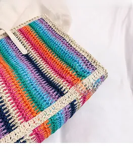 Macro shot showing multi-color woven texture and white handles of the straw tote bag