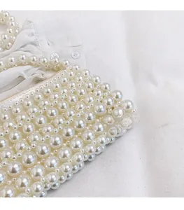 Close-up of handmade pearl weave detail and zipper closure on elegant white bead handbag