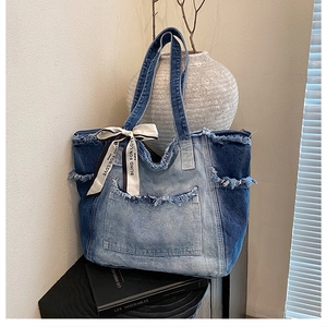 Detail of vintage denim tote bag with gradient blue wash, raw edges, and silk scarf decor