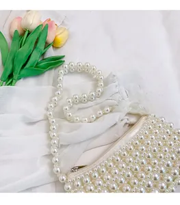 Detailed shot of the woven pearl handbag with tulip and elegant white fabric background
