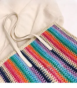 Detail view of colorful rainbow straw weave texture and white leather handles on tote bag