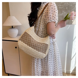 Detail of hand-woven straw shoulder bag with leather strap in a home setting