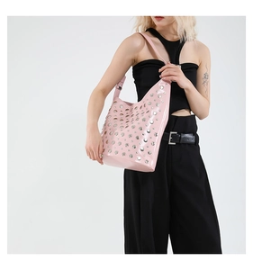 Détail d'un sac à bandoulière rose avec clous argentés porté par un mannequin en noir