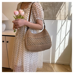 Detail of hand-woven straw bag featuring white diamond hollow pattern and leather strap