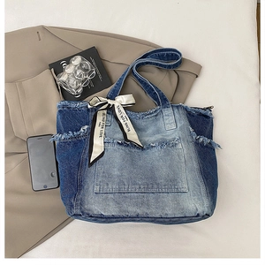Detail of patchwork denim tote bag with frayed edges and decorative silk scarf ribbon