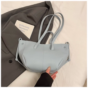 Detailaufnahme der hellblauen Tote-Bag mit Lychee-Muster auf Bett und grauem Sakko