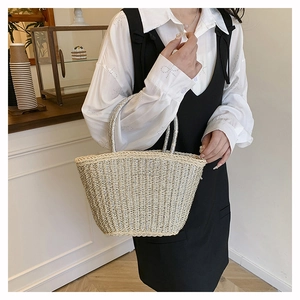 Close-up of woven straw bag with silver thread detail and metallic round handles