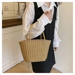 Detail of a handmade straw tote bag featuring horizontal weave and round handles for summer