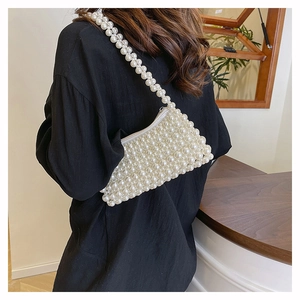 Detail of white handmade pearl beaded shoulder bag worn elegantly under the arm