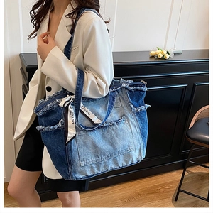 Detail of blue denim tote bag with frayed edges and Blind For Love decorative ribbon
