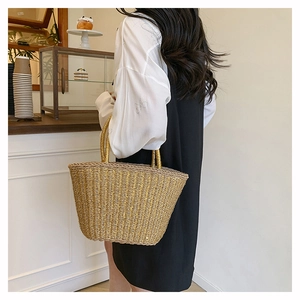 Detail of hand-woven straw bag with gold metallic threads in a lifestyle cafe setting