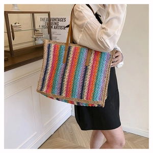 Detailed texture of rainbow straw tote bag with brown leather shoulder straps