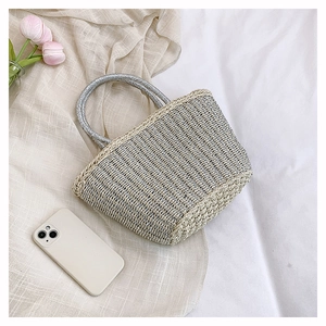 Detail of hand-woven straw tote bag with silver ring handles and glittery metallic accents