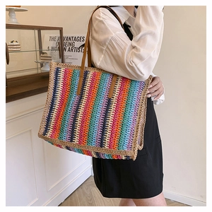 Close-up of colorful striped woven tote bag with brown leather straps for summer beach use